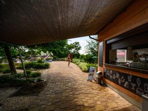 a woman walking down a brick walkway next to a building at Termálhotel Martfű in Martfů