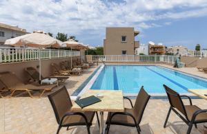 a swimming pool with tables and chairs next to a hotel at Sunny Vibes by Estia Adults Only in Stalís