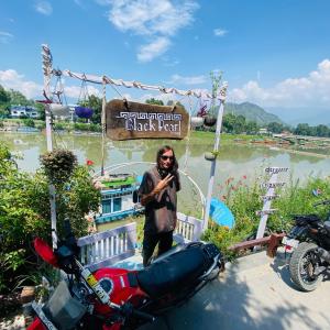 a man standing in front of a black sign next to a motorcycle at Blackpearl in Srinagar