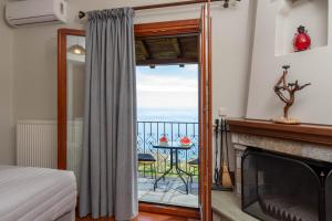 a bedroom with a fireplace and a balcony with a table at Adilon in Tsagarada