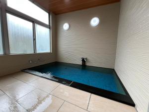 a swimming pool in a room with a large window at Asama Onsen FAN! MATSUMOTO in Matsumoto