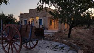 a stone house with a wooden cart in front of it at Casale Mute Terre in Tuglie