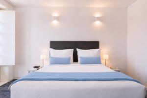 a bedroom with a large white bed with blue pillows at Miragaia - Riverside Suites - Adults Only in Porto
