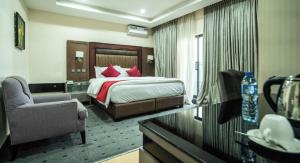 a hotel room with a bed and a chair at Vynedresa Hotel, Abuja in Abuja