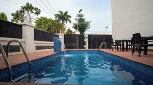 a swimming pool on a deck with a table and chairs at Vynedresa Hotel, Abuja in Abuja