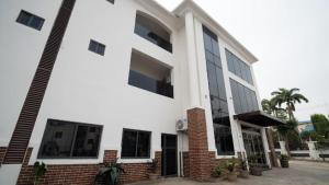 a white building with a palm tree in front of it at Vynedresa Hotel, Abuja in Abuja