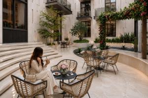 a woman sitting at a table talking on a cell phone at Liora Al Yasmin District in Riyadh