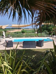 a swimming pool with three black chairs next to it at Gite du Passignac in Saint-Maigrin
