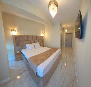 a bedroom with a large bed and a chandelier at Penthouse Rico in Eforie Nord