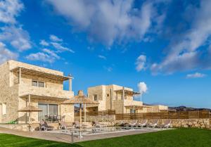 a stone building with chairs and umbrellas at Villa Thea in Triopetra