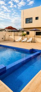a swimming pool with chairs and umbrellas on a building at Executive Cozy Suite at THE HIDDEN DOMUS I Saltpond Suite in Madina