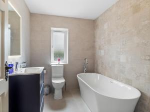 a bathroom with a tub and a toilet and a sink at Connemara Bay House in Moyard +35 photos
