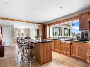a kitchen with wooden cabinets and a island with bar stools at Connemara Bay House in Moyard