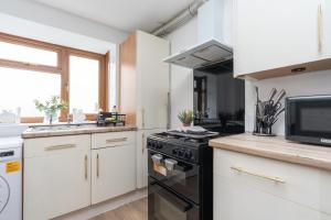 a kitchen with white cabinets and a black stove top oven at Open Mind Property - 3BR with Free Parking & Garden in Portsmouth