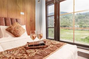 a bedroom with two glasses of wine on a bed at kanwal cottages safa resort in Dandpur