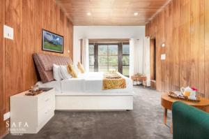 a bedroom with a large white bed and wooden walls at kanwal cottages safa resort in Dandpur