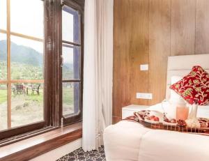 a bedroom with a white bed and a window at kanwal cottages safa resort in Dandpur +7 photos