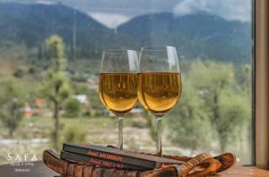 two glasses of wine sitting on top of a table at kanwal cottages safa resort in Dandpur