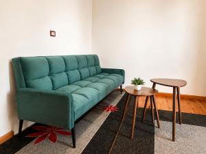 a green couch in a living room with two tables at Villa Hodo in Vlorë +28 photos