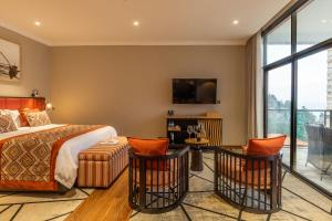 a bedroom with a bed and two chairs and a tv at LUX* Lake Kivu 