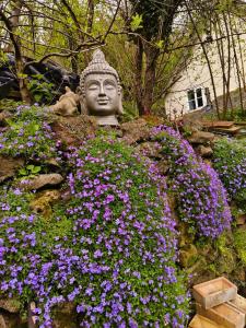 a statue in a garden with purple flowers at Tranquil Woodland Cottage by river Wye in Lydbrook