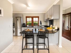 a kitchen with a island with two bar stools at Captains Quarters in Plettenberg Bay