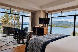 a bedroom with a bed and a desk with a television at LUX* Lake Kivu 