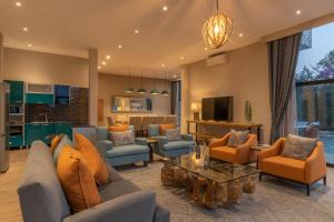 a living room with a couch and chairs and a tv at LUX* Lake Kivu 