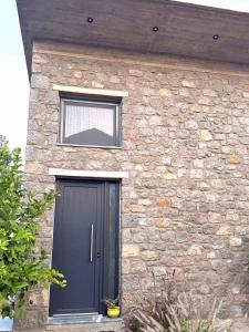 a stone house with a black door and a window at Casa del Quadro in Chios