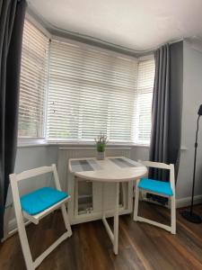 a table and two chairs in a room with windows at Spacious Double Studio-style room in Orpington