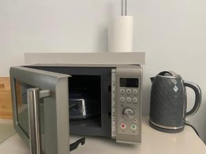 a microwave oven sitting on a counter with a cup at Spacious Double Studio-style room in Orpington