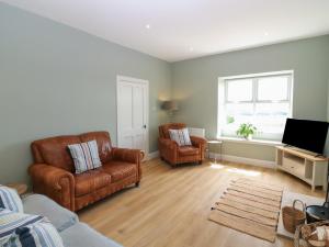 a living room with two chairs and a television at Keepers Cottage in Haddington