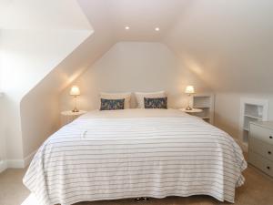 a bedroom with a large white bed with two lamps at Keepers Cottage in Haddington