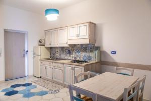 a kitchen with white cabinets and a table and a refrigerator at Agriresort La Dragonara in Bacoli