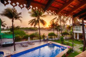 a swimming pool in a house with palm trees at Resort Coqueiral - A Portuguese Heritage Stay by the Sea in Candolim