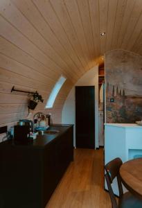 a kitchen with a wooden ceiling and a table at luxury cottage with sauna in Milsbeek