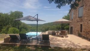 a patio with a table and chairs and an umbrella at Chez Patoue Gîte et Chambre d'hôtes in Sanvensa