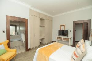 a bedroom with a bed and a tv and a chair at Bevuline in Gqeberha