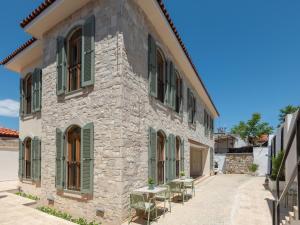a stone house with green shutters and tables outside at The Mint Urla in Kuscular