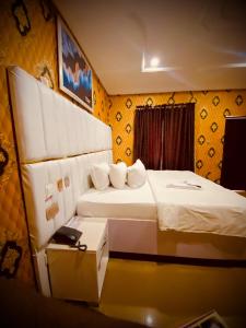two beds in a room with yellow walls at Rotana Hotel and Suits in Ilorin +6 photos