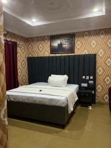 a bedroom with a bed with a black headboard at Rotana Hotel and Suits in Ilorin