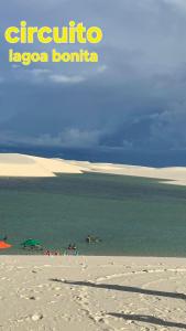 a beach with a group of people in the water at Pousada Recanto Sapoti in Barreirinhas