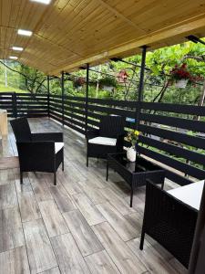 a patio with chairs and tables and a wooden roof at Будинок під Менчулом in Rakhiv