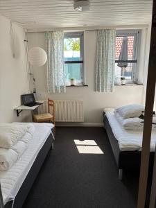 a bedroom with two beds and a desk and two windows at Ibsens Gaard in Ebeltoft +44 photos