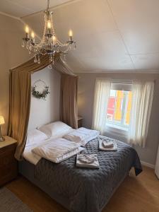 a bedroom with a bed with a chandelier and two shoes on it at Finnegården Røros in Røros