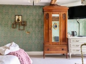 a bedroom with a wooden cabinet and a dresser at Plas Dolguog in Machynlleth