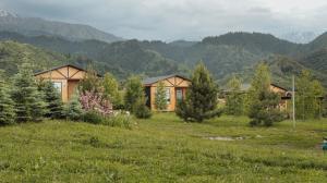 a house in a field with mountains in the background at Aglamp Almaty in Besqaynar