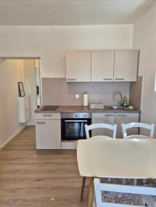 a kitchen with white cabinets and a table and chairs at Guesthouse Maro in Povljana