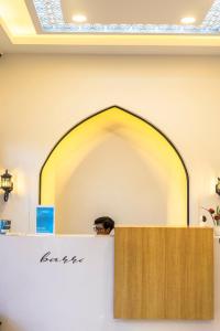 a man is standing behind a counter in a room at Al Barra Syariah Hotel in Bukittinggi