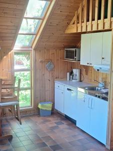 a kitchen with white appliances and a wooden ceiling at Brufoss Hytte og Laksesenter in Svarstad